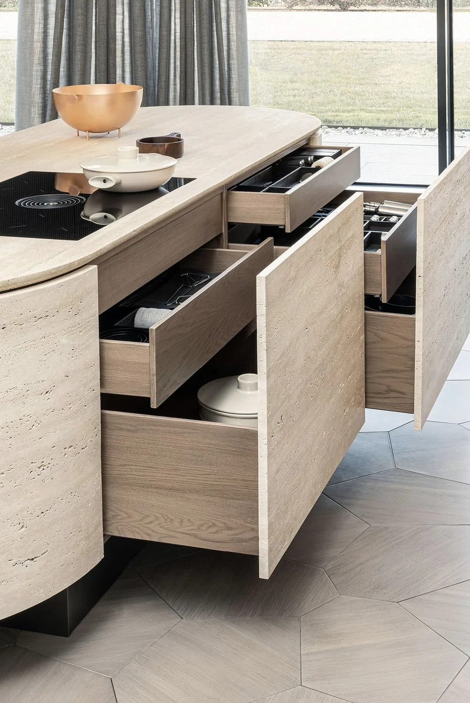 Open drawers inside the same travertine kitchen island, revealing fitted internal storage