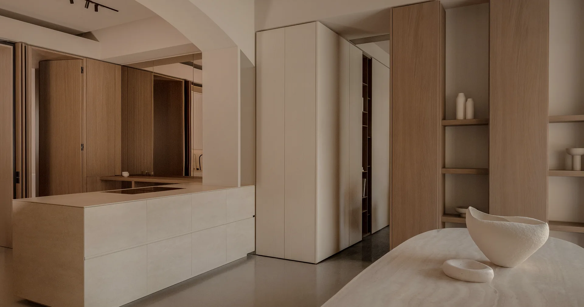 Living-space cabinetry with a mirrored recess, concealed doors and open timber display shelves