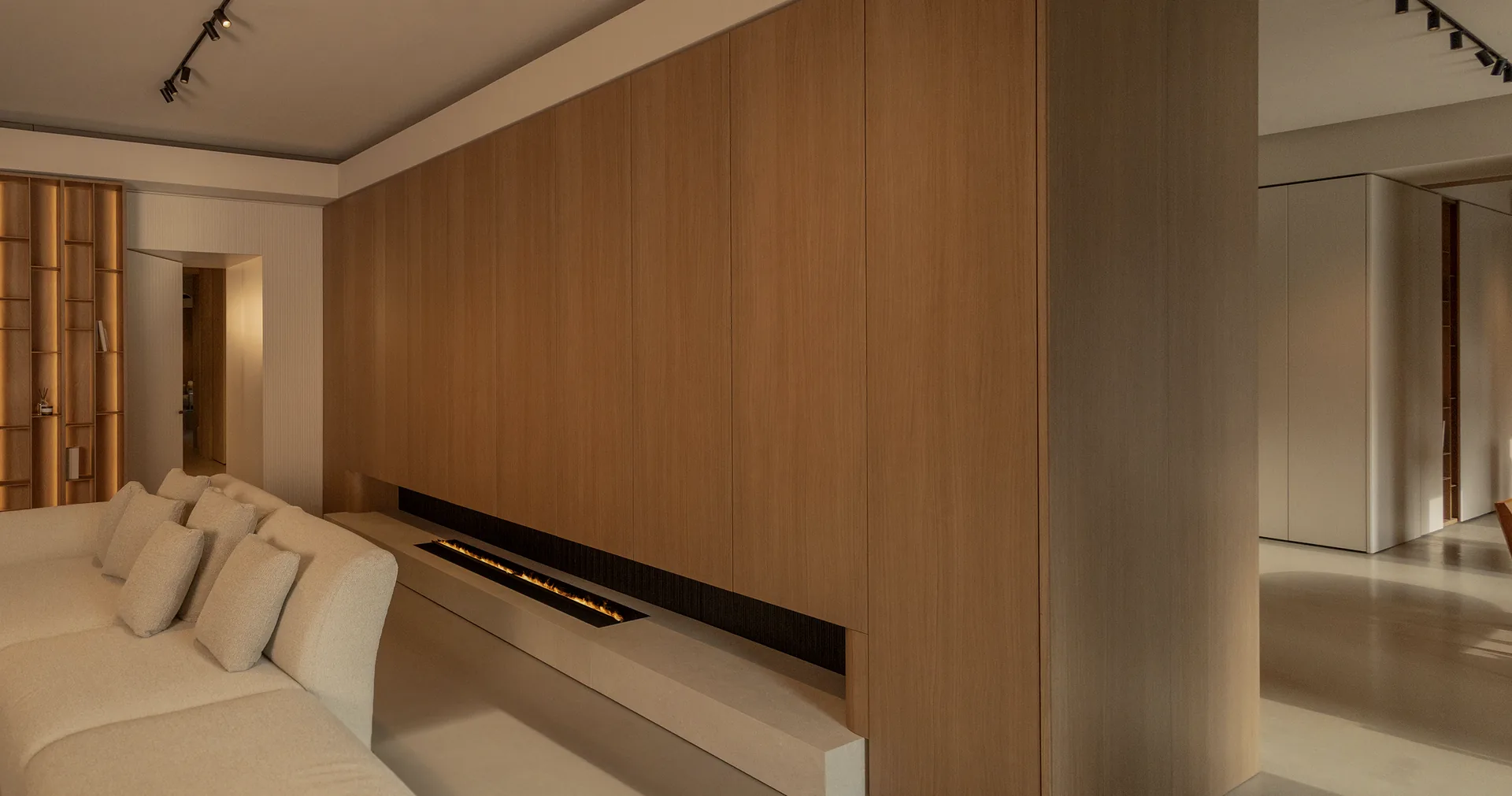 Full-height timber wall paneling above a linear fireplace, with a concealed door connecting the living spaces