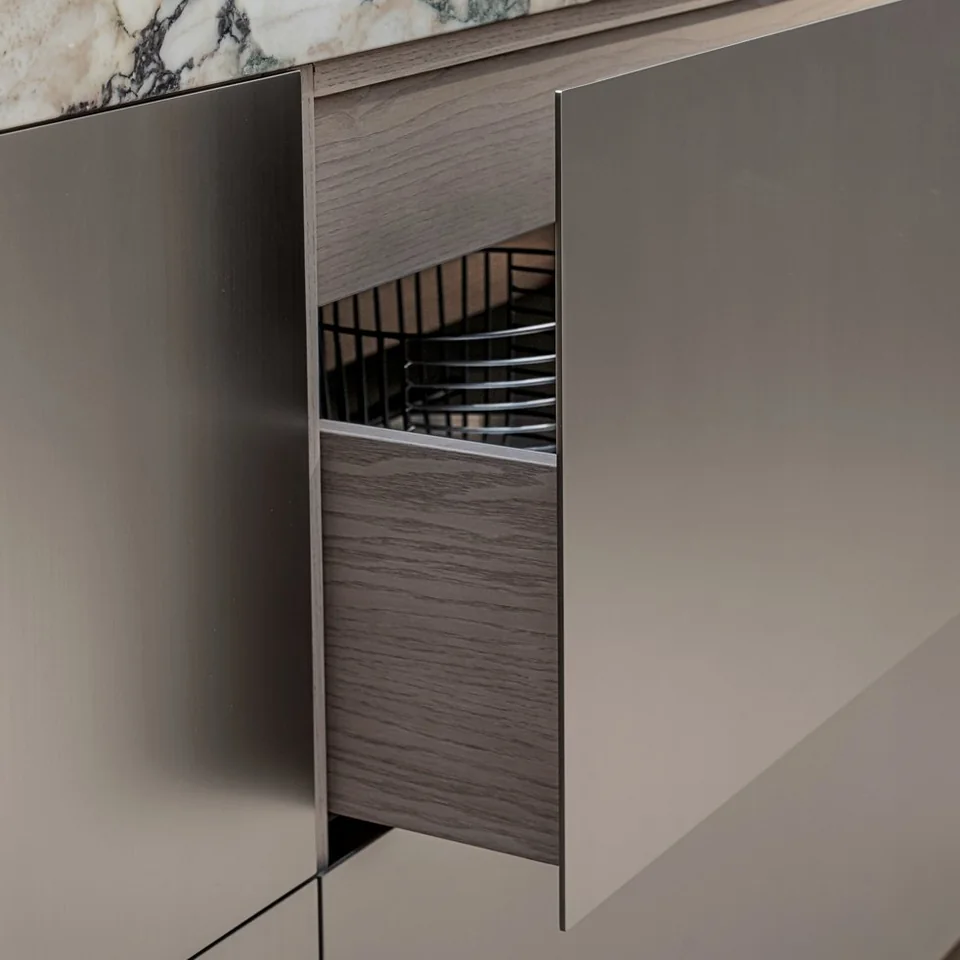 Open metal drawer beneath a stone worktop, showing its thin edge and fitted interior